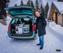 Dag Kristoffer Andreassen fra Teknisk Museum står på snødekte Persbråten med åpen bakdør og viser fram en stappfull stasjonsvogn med datamaskiner og tilbehør.